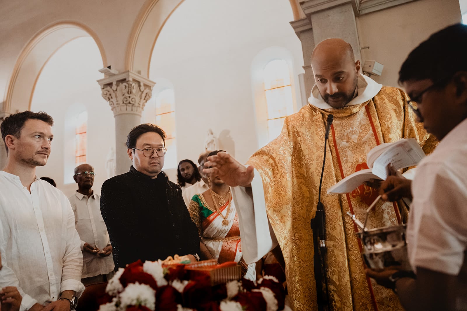 Bénédiction prêtre mariage religieux franco-indien Lyon Prêtre bénissant les offrandes pendant une cérémonie de mariage multiculturel à Lyon