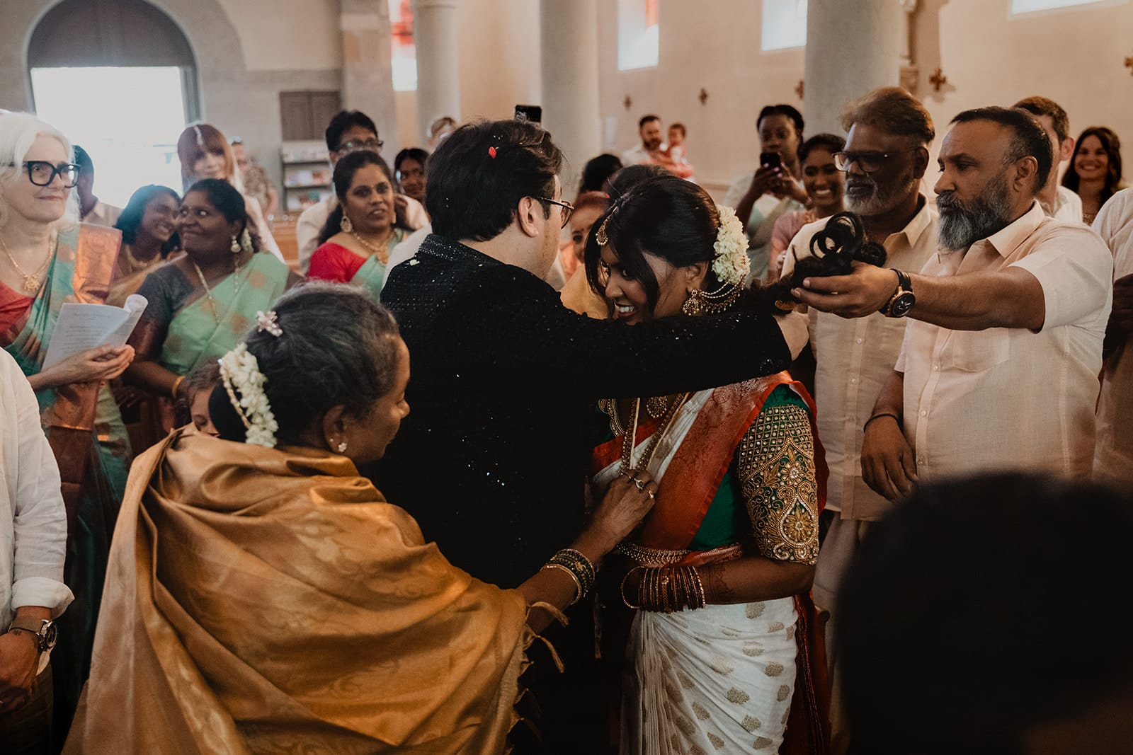 Rituel du thaali mariage indien Lyon Marié nouant le collier traditionnel autour du cou de la mariée lors d’un mariage indien à l’église
