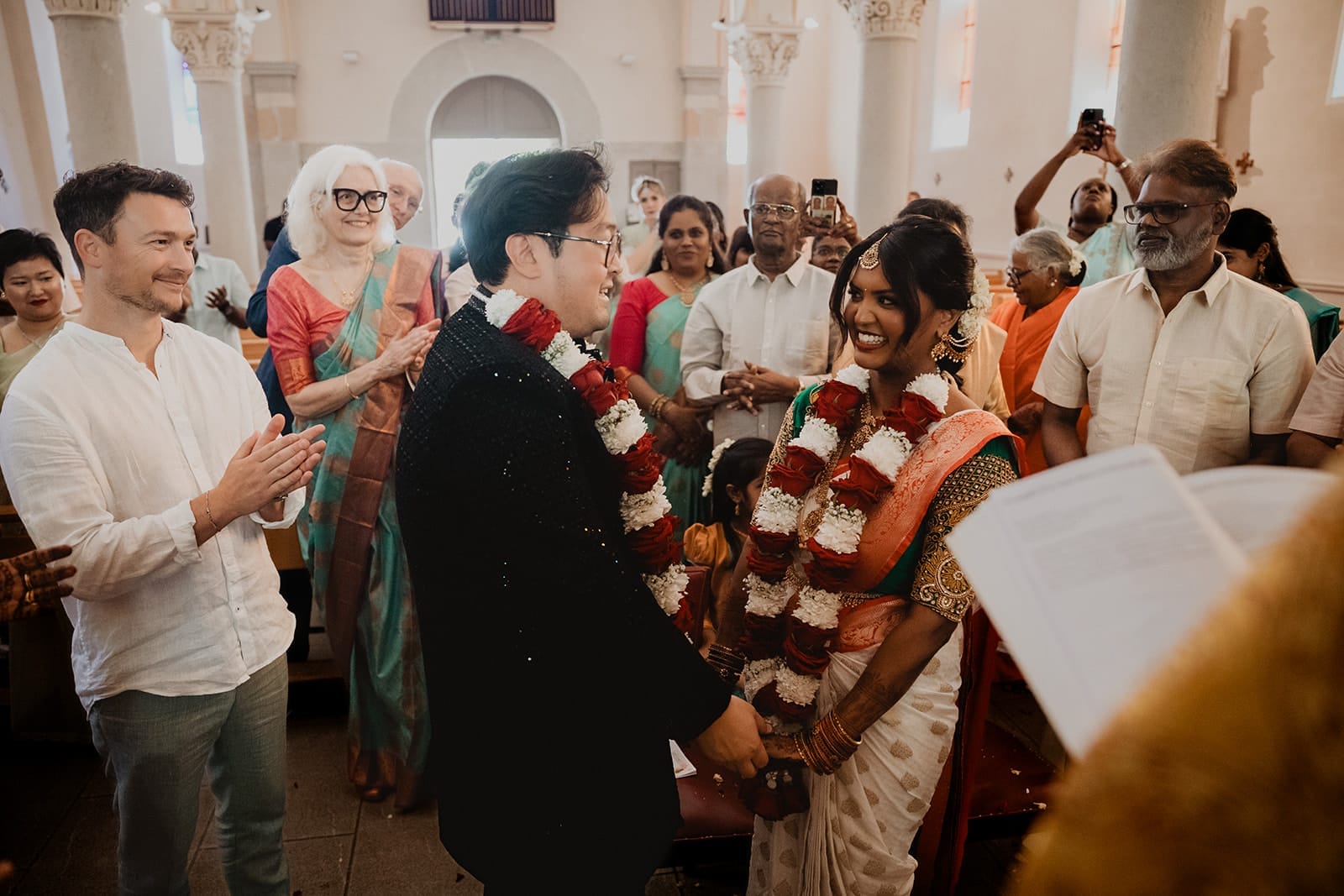 Mariés souriants après l’échange des guirlandes lors d’un mariage indien à l’église