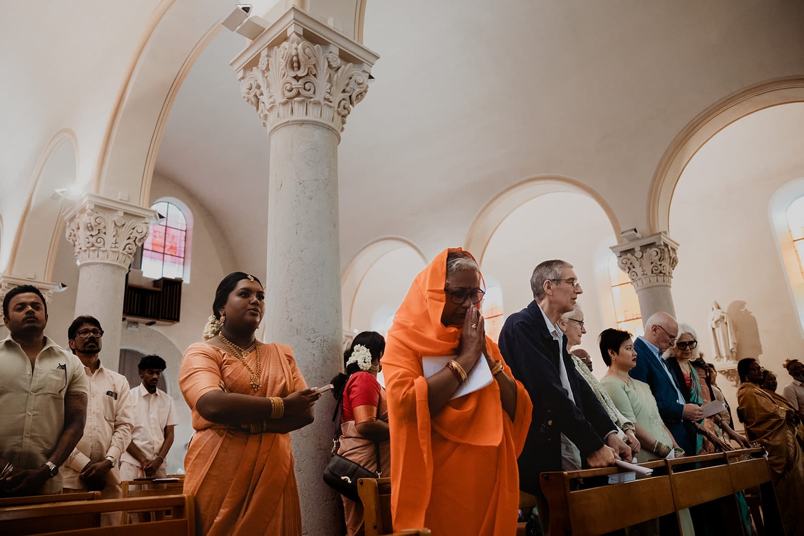 Invités debout dans l’église pendant une cérémonie de mariage multiculturelle