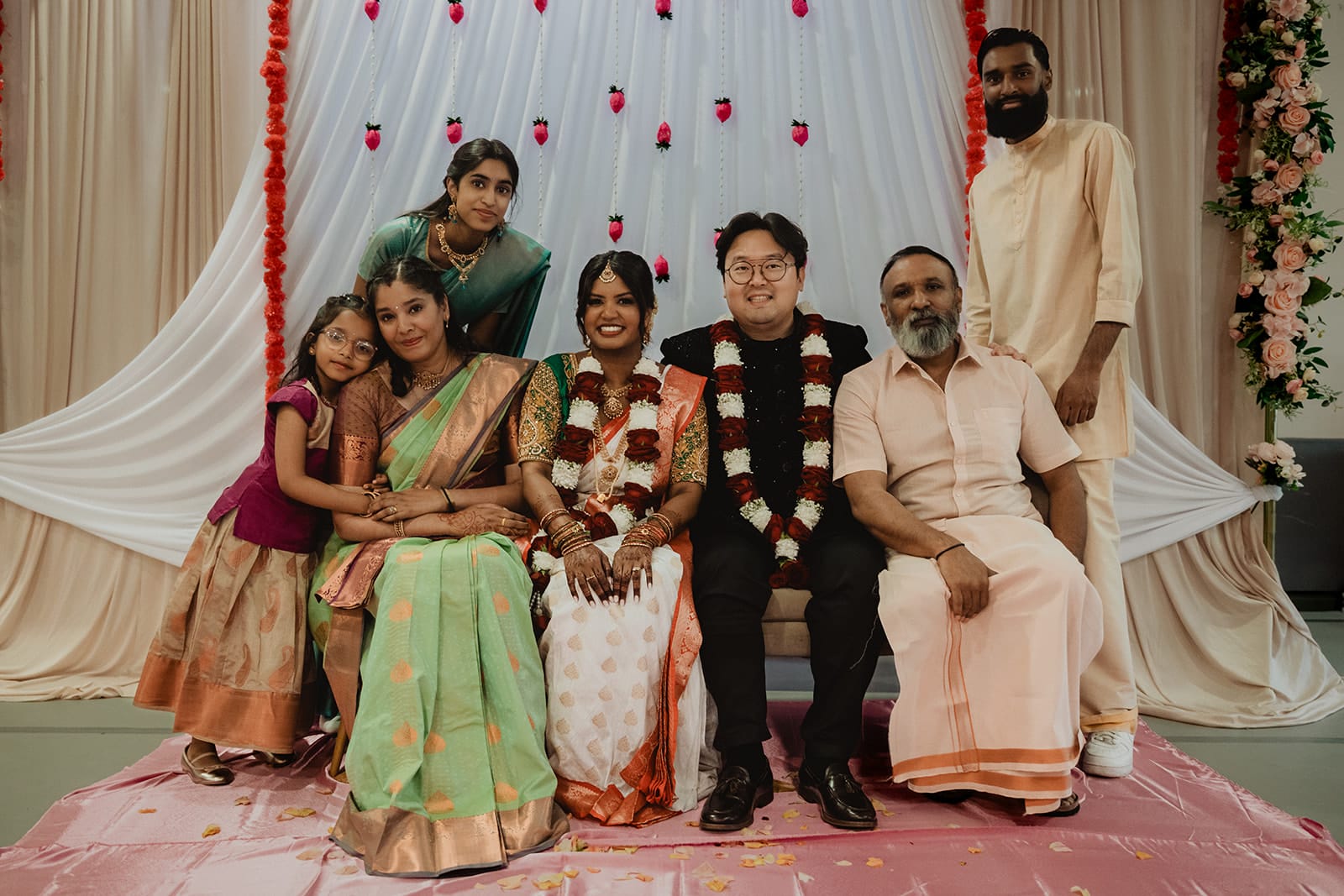 Famille, piliers et sourires Photo de famille pendant un mariage multiculturel entre traditions indiennes et coréennes