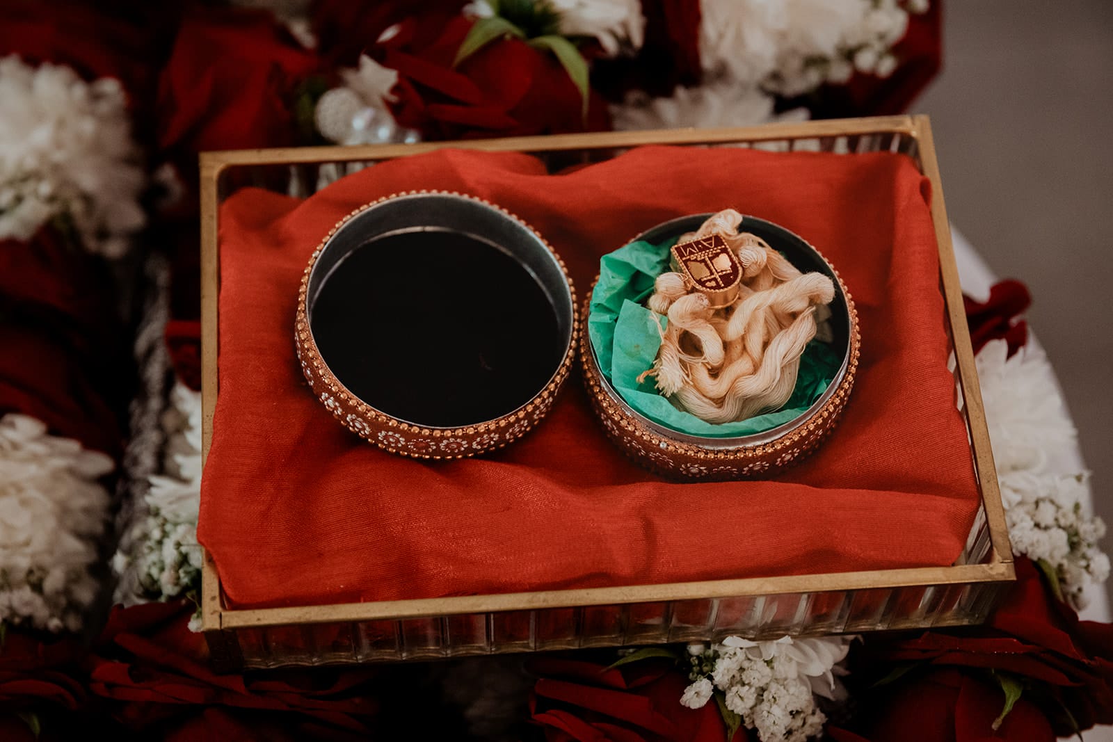 Coffret rituel mariage indien Lyon Coffret traditionnel de mariage indien avec fil sacré et pâte noire, posé sur un tissu rouge