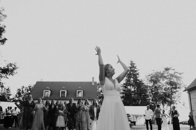Mariée lançant son bouquet devant les invitées au Domaine de la Pierre