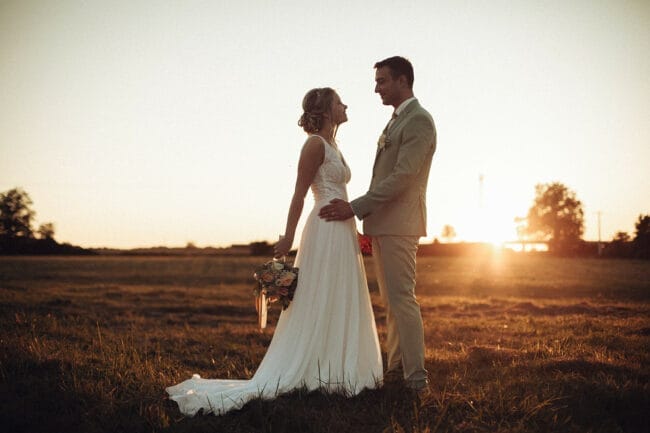 Couple de mariés au coucher du soleil dans un champ près du Domaine de la Pierre