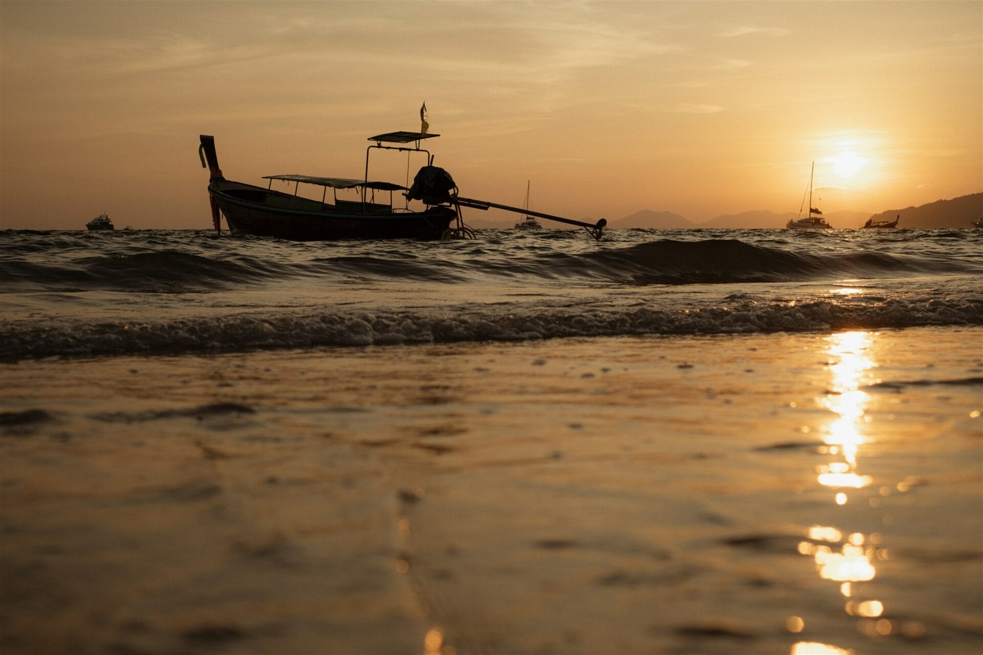 Bateau au coucher du soleil, photographié depuis le bord de l’eau, dans une lumière dorée et apaisée.