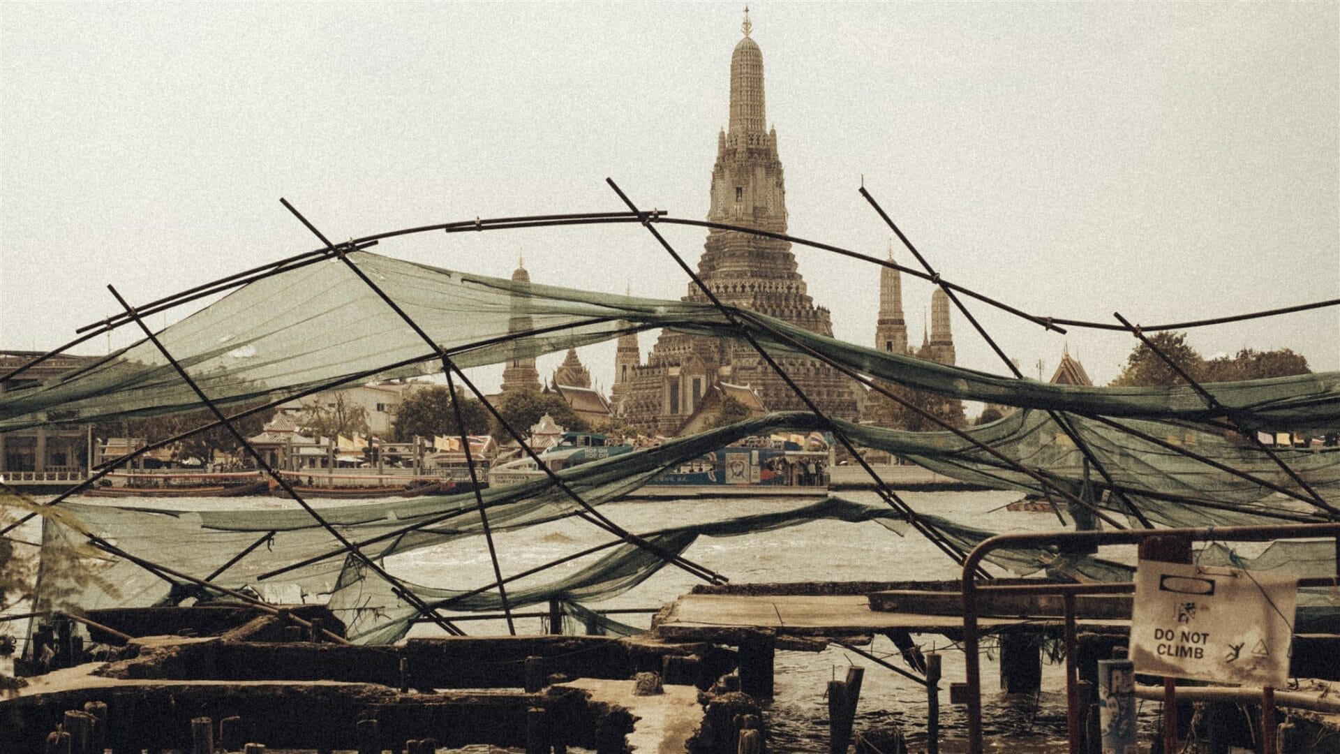 Vue du temple Wat Arun à Bangkok à travers des filets verts déchirés au bord du fleuve Chao Phraya.