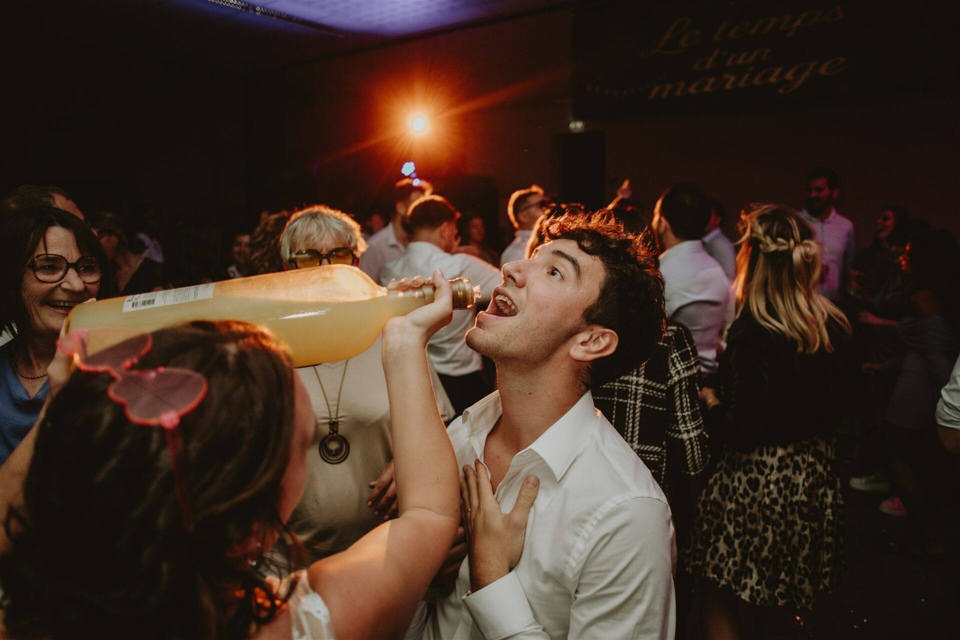 Invité qui boit au goulot sur la piste pendant une soirée de mariage festive
